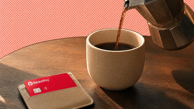 Red RedotPay card in a card holder on a table beside a cup of coffee being poured