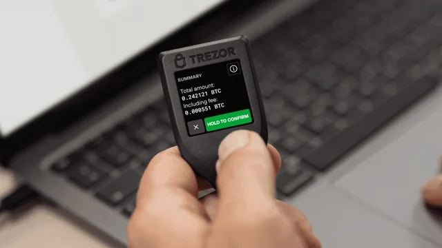 A person holding a genuine Trezor Model T in the official product photograph