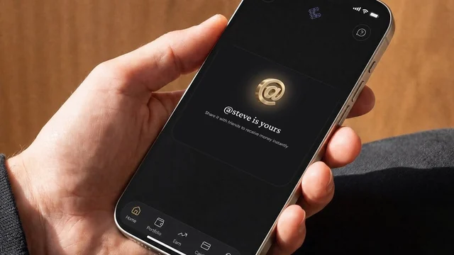 A hand holding a phone in the ether.fi app showing a gold @ symbol and the message @steve is yours, share it with friends to receive money instantly