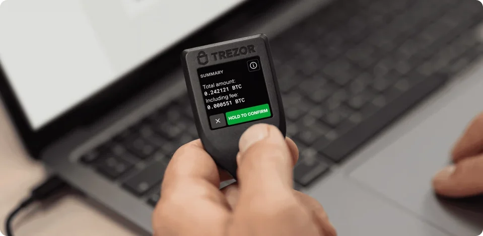 A person holding a genuine Trezor Model T in the official product photograph