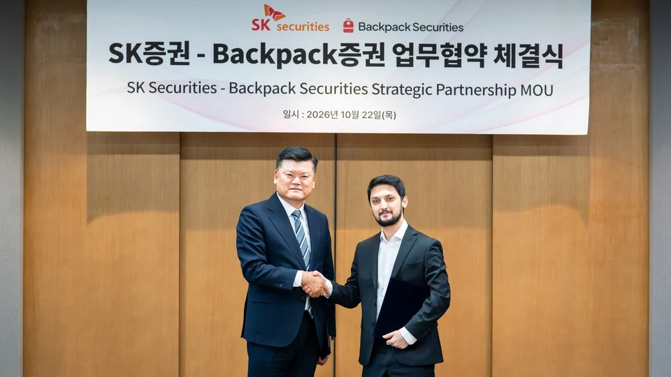 Two executives shake hands under a banner for the SK Securities and Backpack Securities strategic partnership MOU