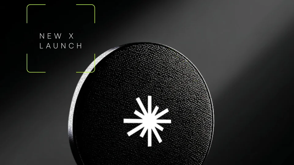 Black coin with the white Axis Robotics star mark under a beam of light, beside a green-framed label reading New X Launch