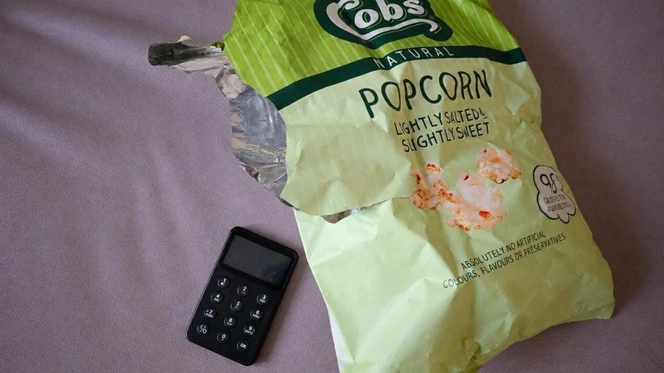 A SafePal X1 hardware wallet lying next to an opened bag of popcorn on a sofa, from SafePal's Halloween movie-night post